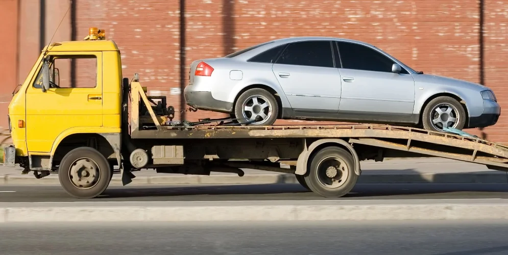 A car is being towed on the back of a truck.